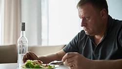 Мужчина с алкогольной зависимостью ест салат